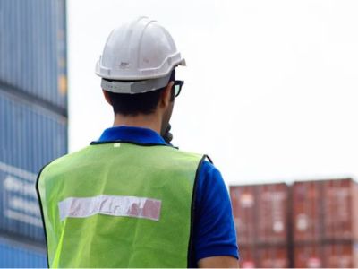 Operaio con elmento in mezzo ai container