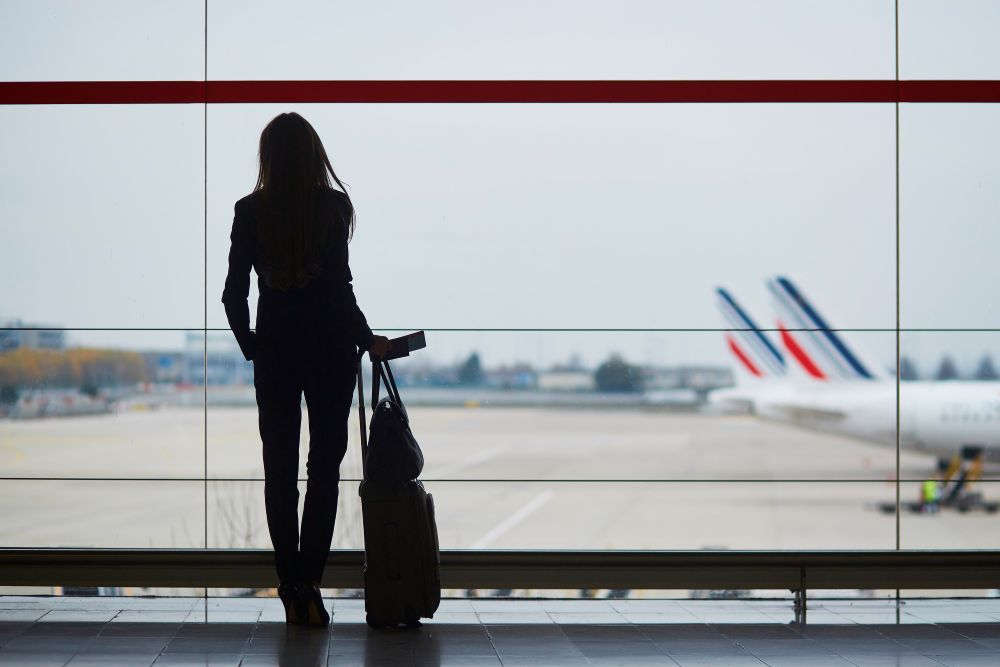 vrouw op vliegveld kijkend naar landingsbaan