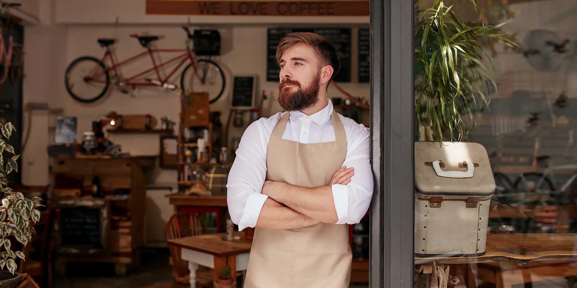 Meżczyzna z założonymi rękoma stojący przed sklepem