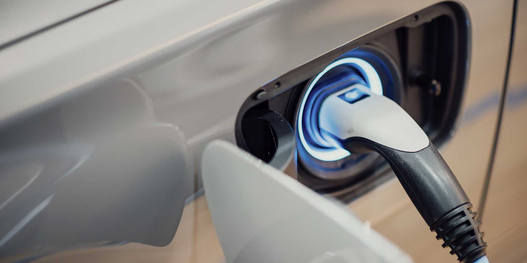 Otwarte gniazdo ładowania elektrycznego i wpięta ładowarka samochodowa