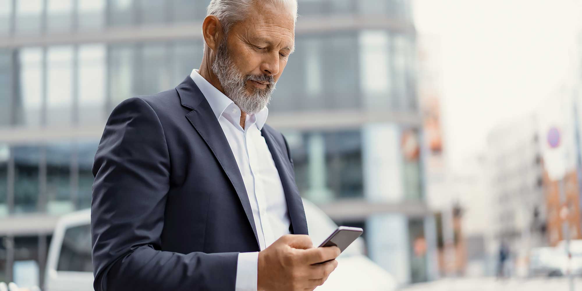 Biznesmen spogląda w telefon po środku miasta