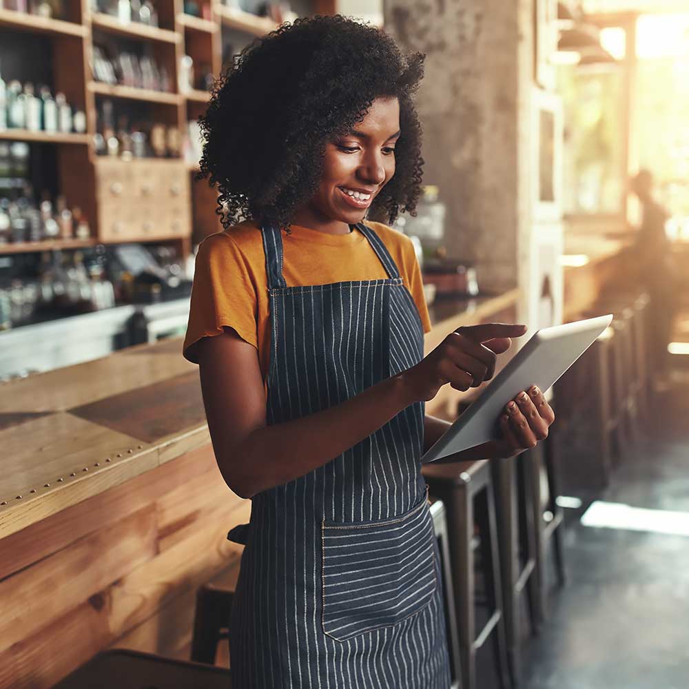Pracownica sklepu z uśmiechem przegląda tablet w dłoni