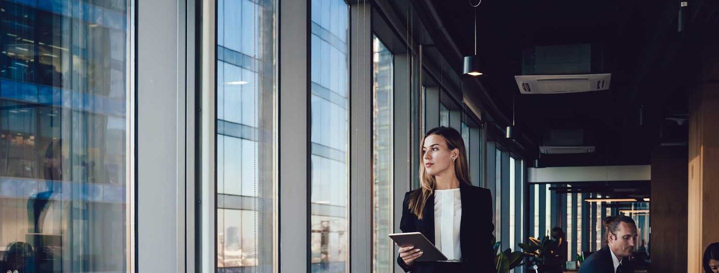 female walking in office setting with tablet in hand