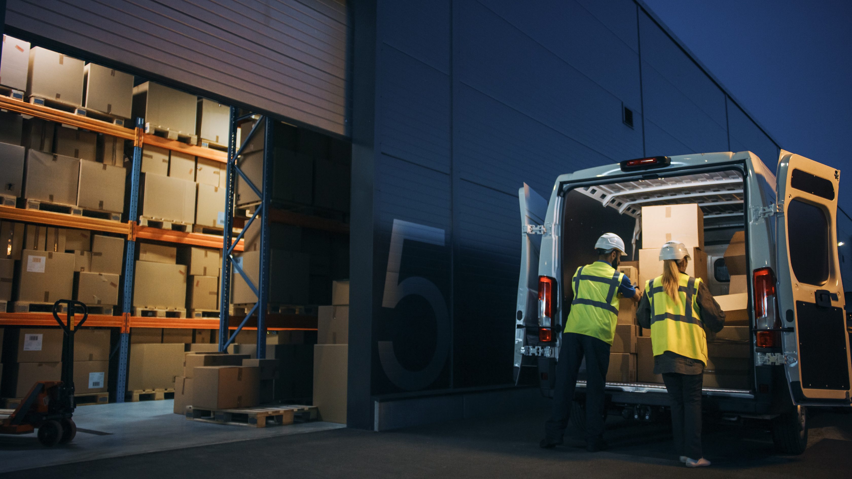 two workers packing a van with high visibility vests on
