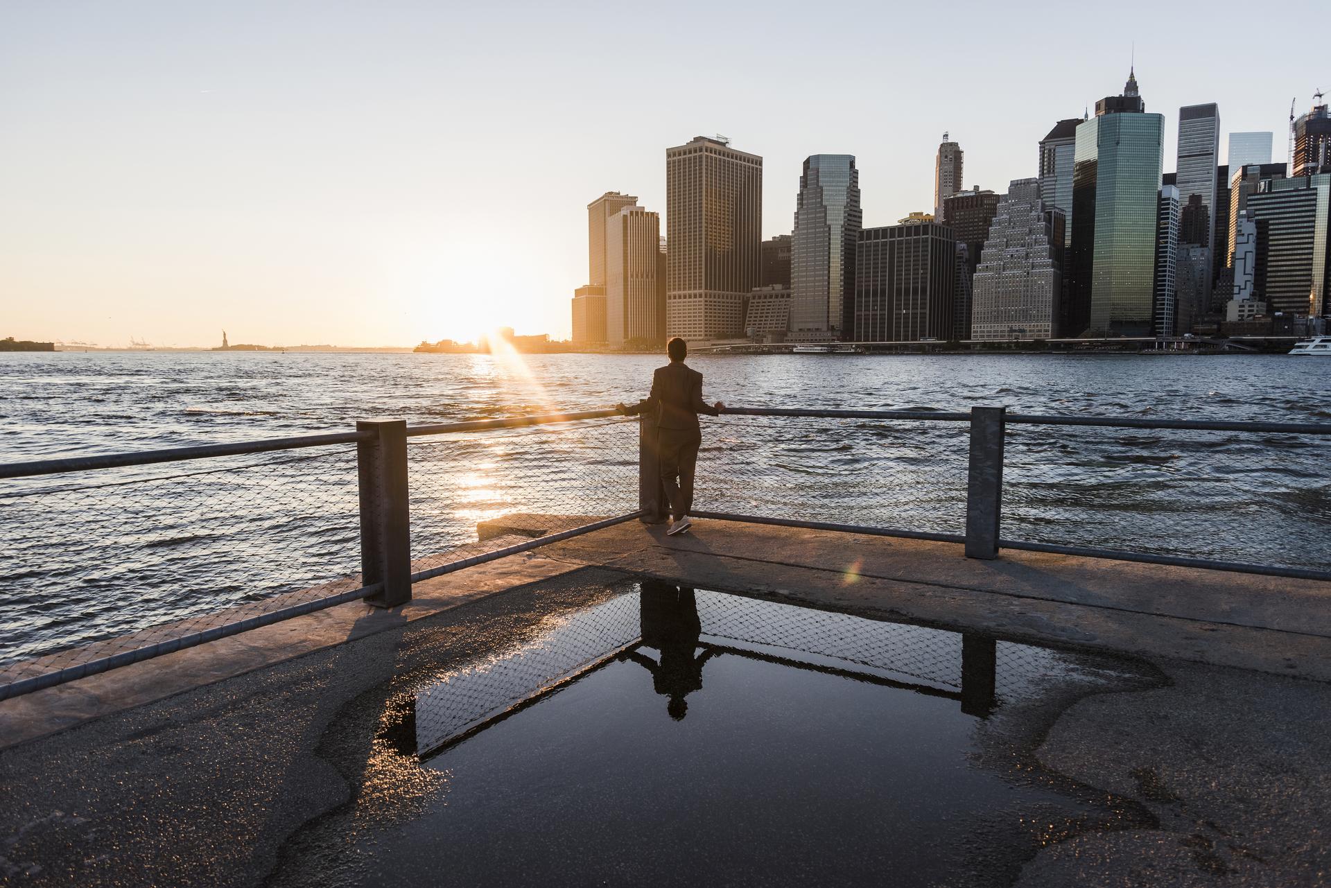 person standing at edge of dock looking out at sunset