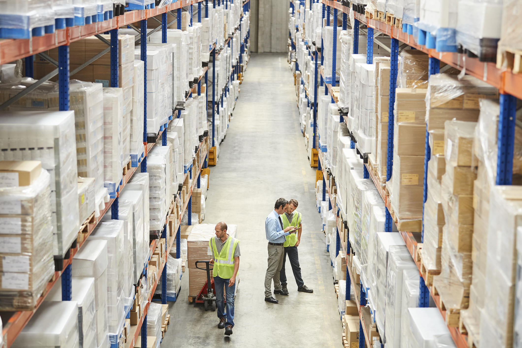 warehouse setting with inventory on shelves and three workers standing on floor