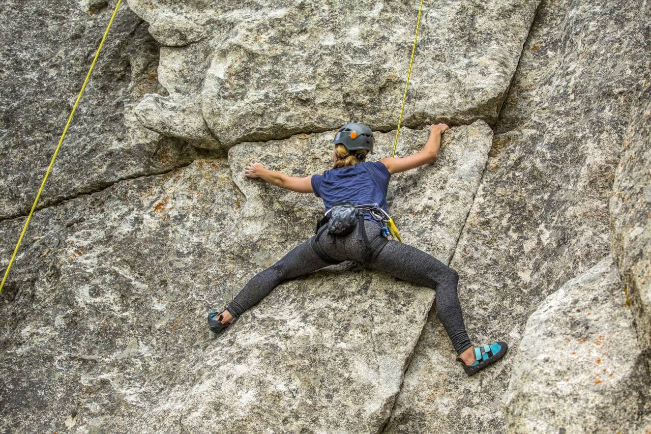 women scaling a rock wall