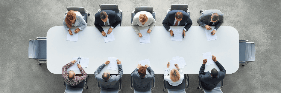 overhead-top-view-of-a-business-panel-collaborating-during-an-office-meeting, gathered-around-a-large-table-to-discuss-strategies-and-ideas