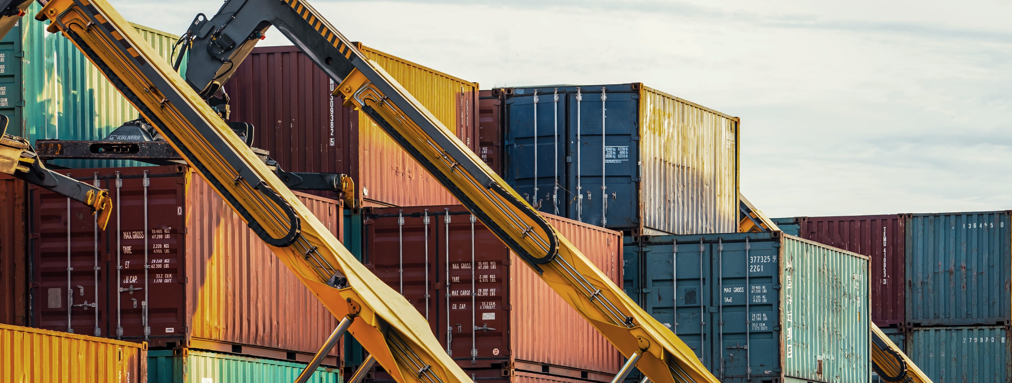 3 shipping container cranes with shipping containers in background