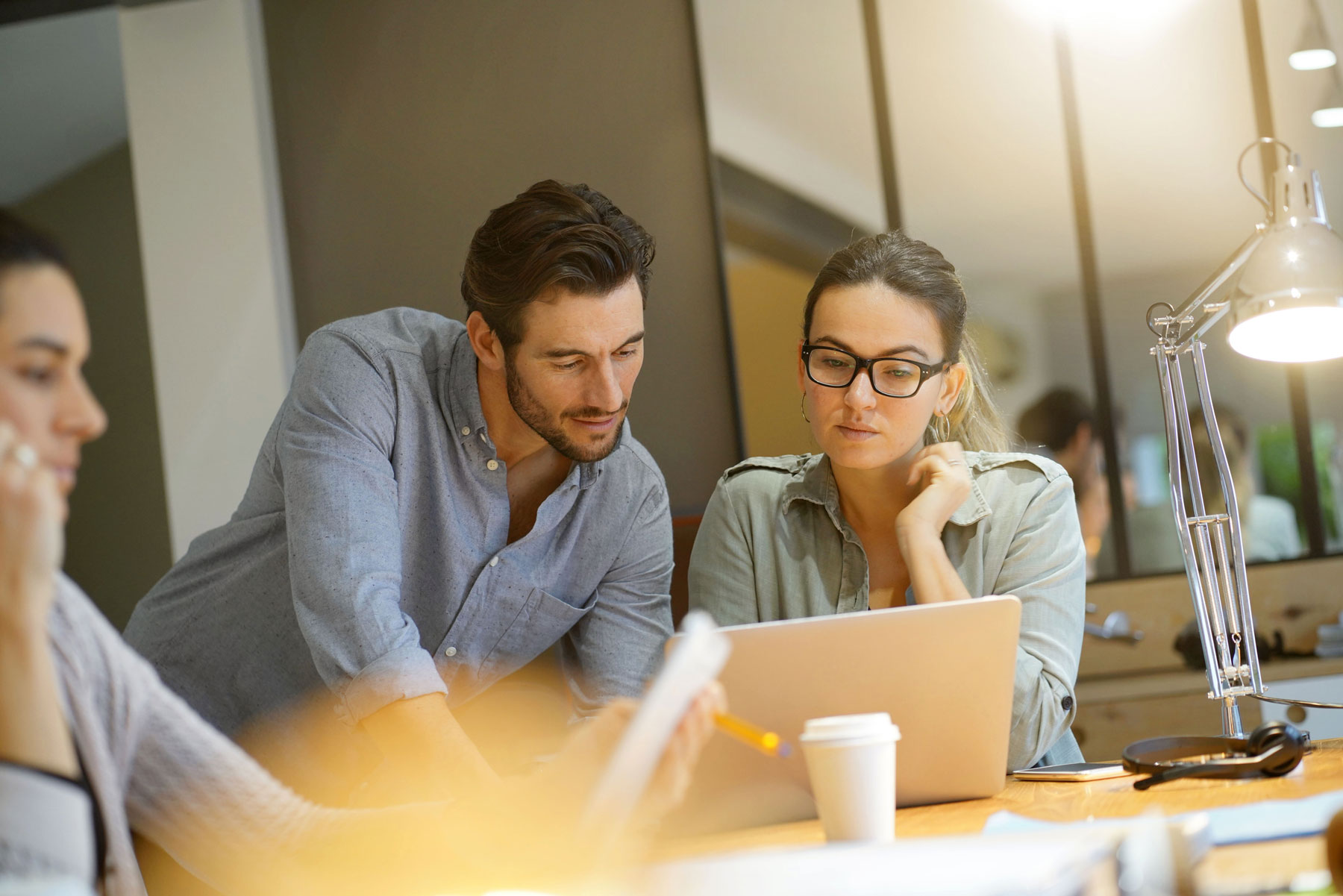 man and woman looking down at computer