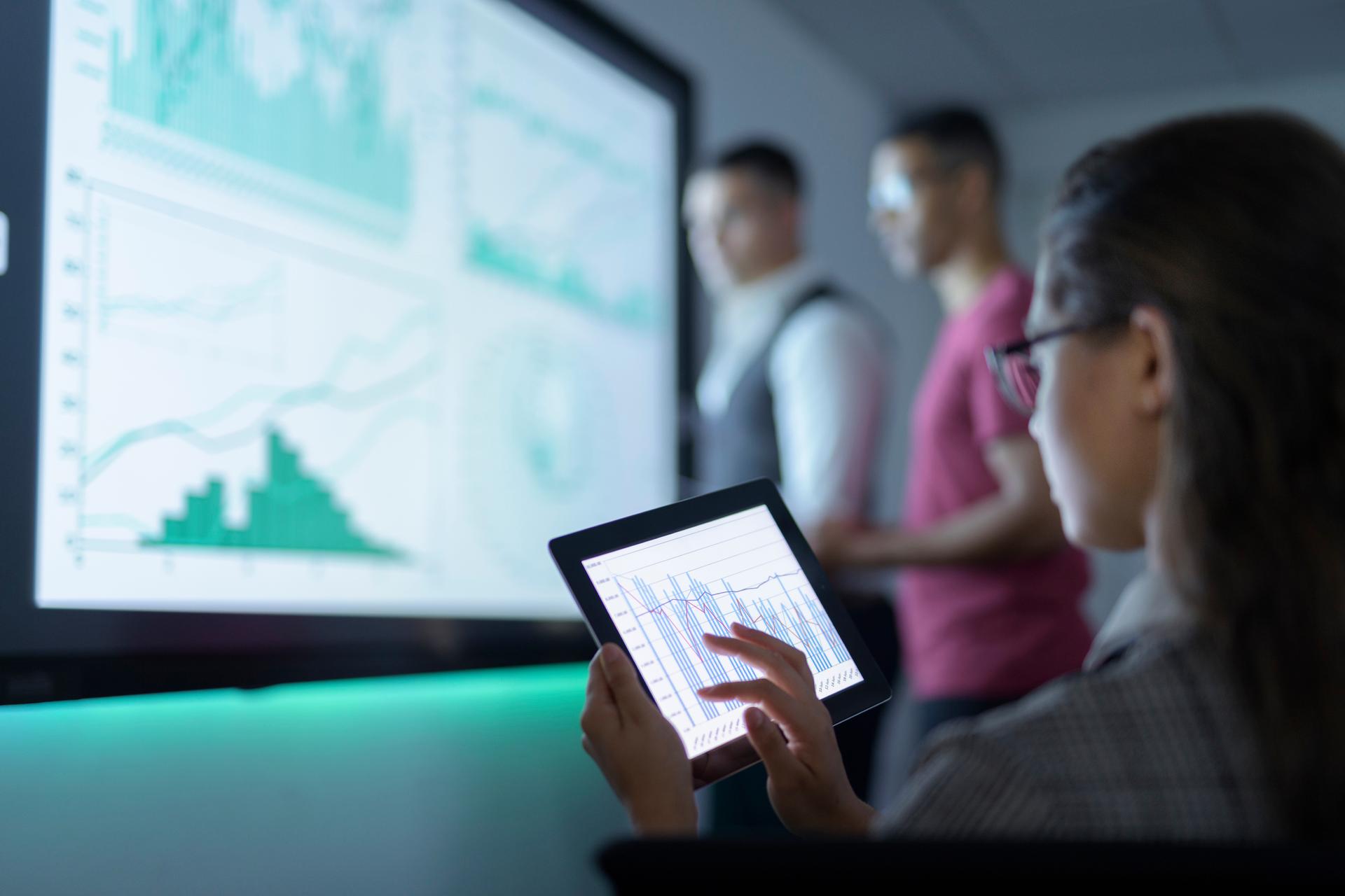 woman holding tablet and charts in background