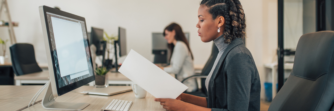 woman sitting at workdesk and looking at paper