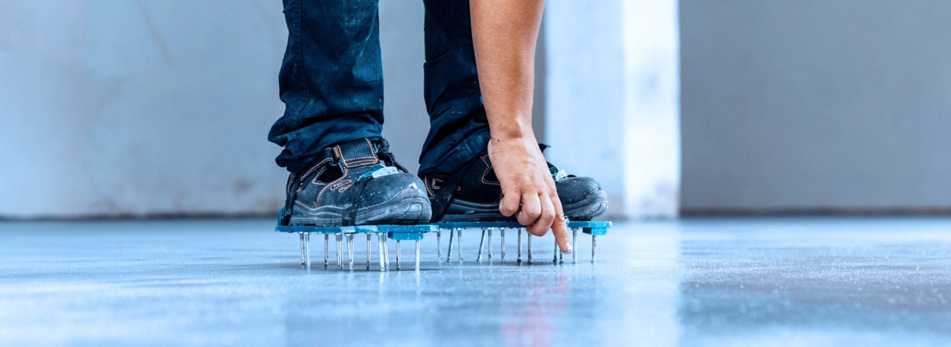 Un operaio edile lavora su una superficie, indossando scarpe chiodate per una maggiore aderenza e stabilità
