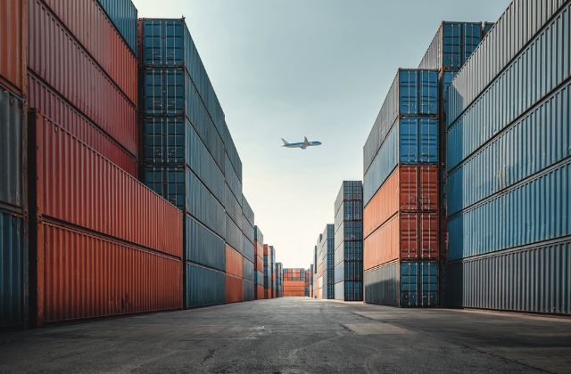 Aereo che vola in cielo aperto circondato da container colorati 