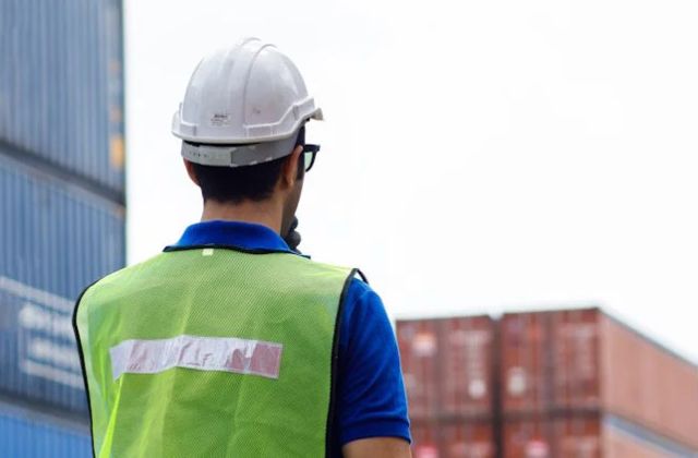 Operaio con elmento in mezzo ai container