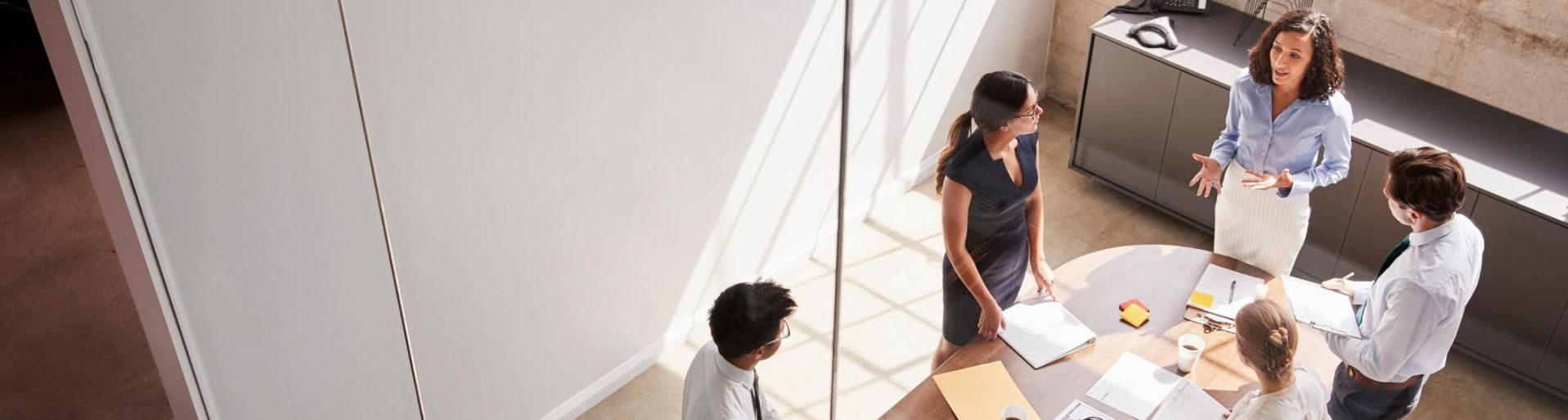 Sei colleghi in piedi intorno a un tavolo in una sala riunioni