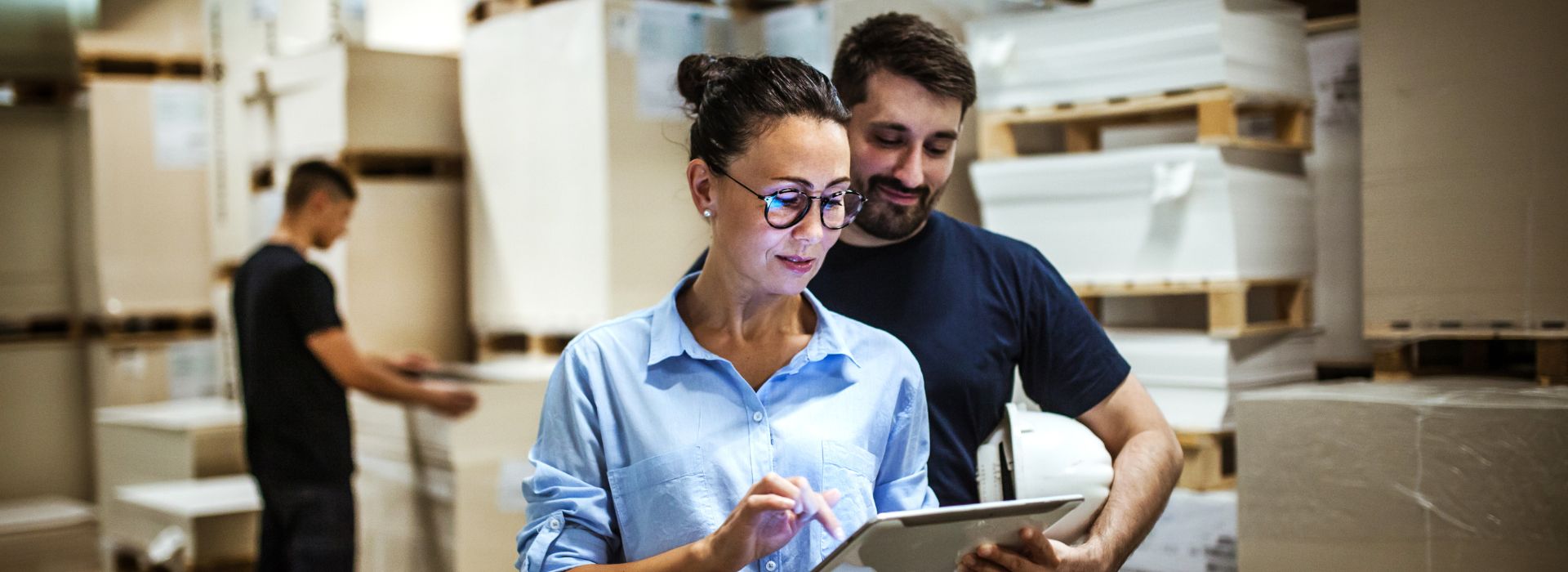 Una manager con un tablet e due operai lavorano in un magazzino 