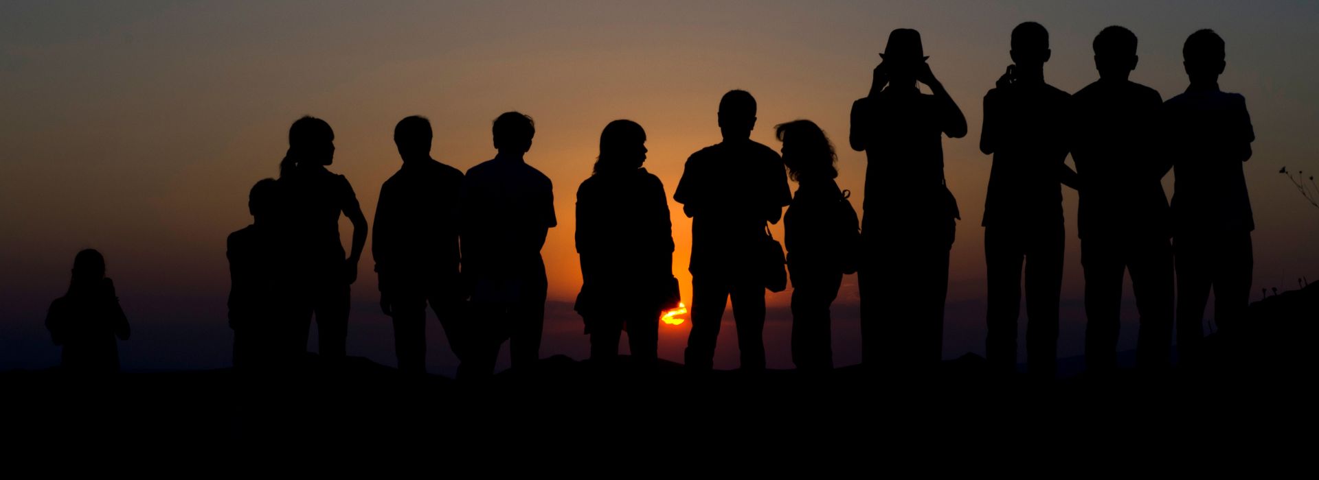 Persone in piedi, in ombra, al tramonto