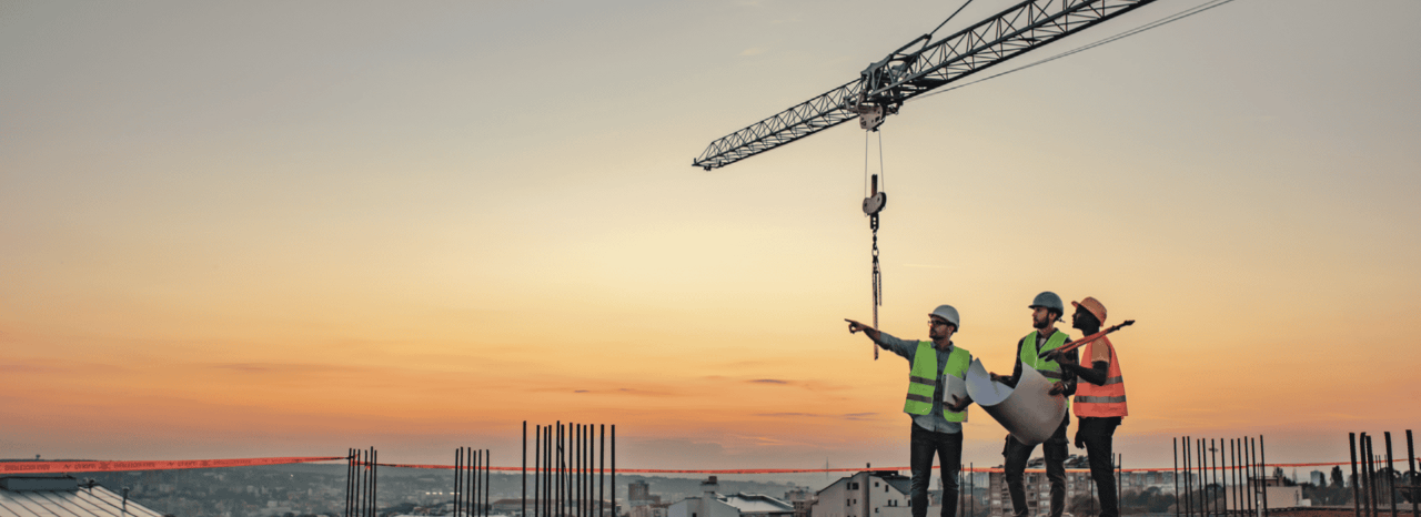 três trabalhadores com pôr de sol ao fundo