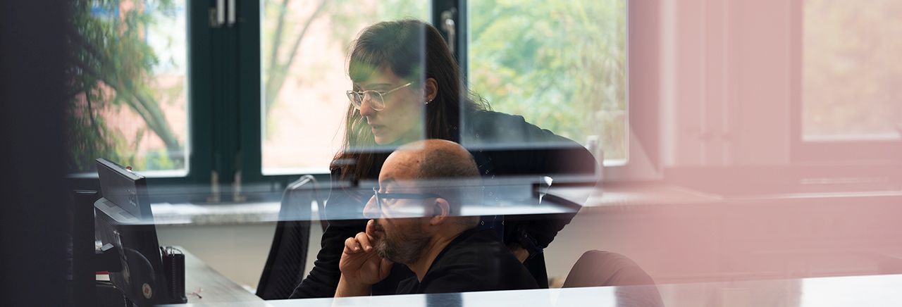 wirtschaftskriminalitaet frau und mann sitzen vor bildschirm computer laptop